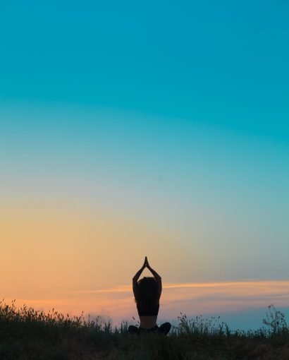 Silhouette of young woman is practicing yoga at sunset